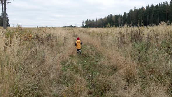 Boy Child in a Yellow Vest and Red Hat Runs