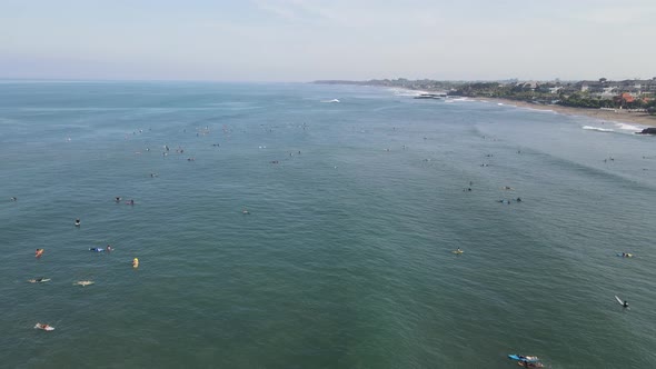 Aerial view of people surfing on waves with surfboards when vacation in Bali, Indonesia .