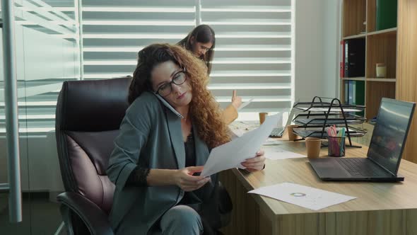 Business woman in office nervously waving her foot on a phone call being unhappy with business repor