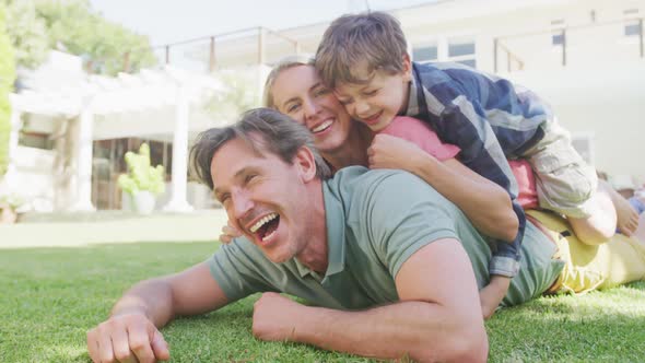 Portrait of happy caucasian couple with son lying in garden