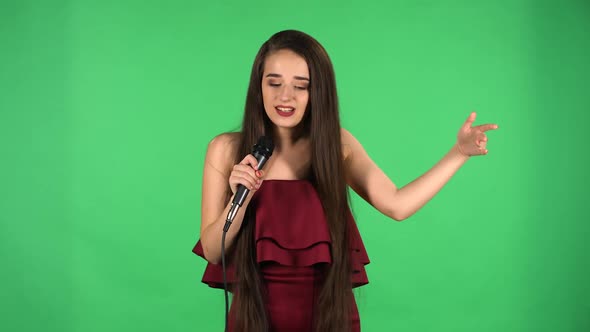 Portrait of Beautiful Young Woman Looking at Camera Sings Song Into Microphone and Dances to Music
