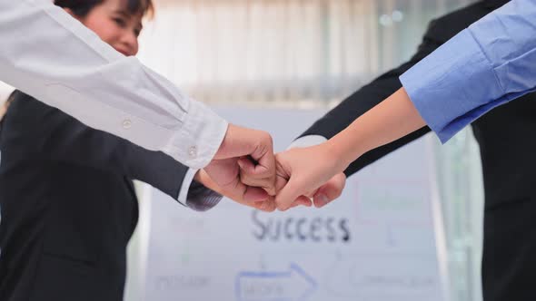 Group of businessman and woman fist bump together to motivate for corporate success in meeting.