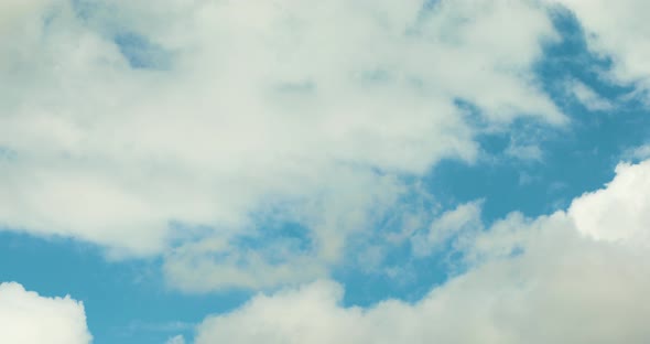 White clouds fly across a bright blue sky