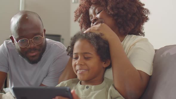 Cheerful African American Parents and Kid Using Tablet at Home