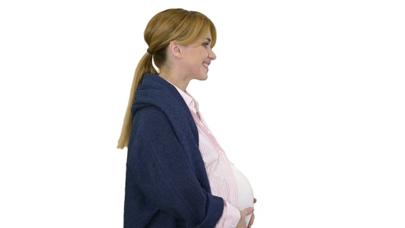 Pregnant lady walking and smiling on white background.