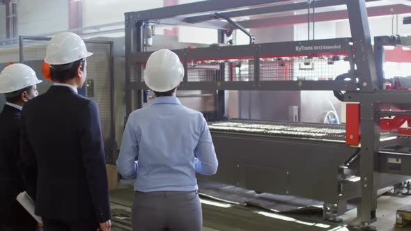 Three Colleagues Watching Manufacturing Process at Compressor Plant