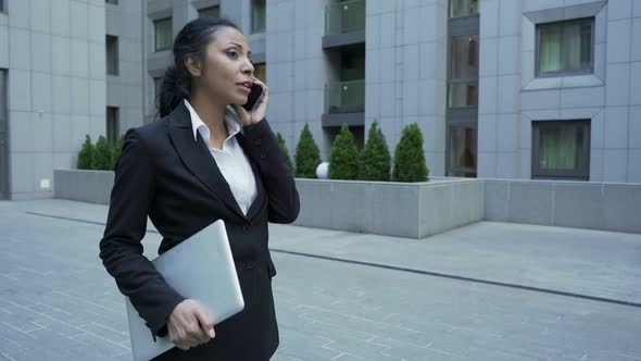 Lady in Business Suit with Laptop Having Informal Chat on Phone, End of Work Day