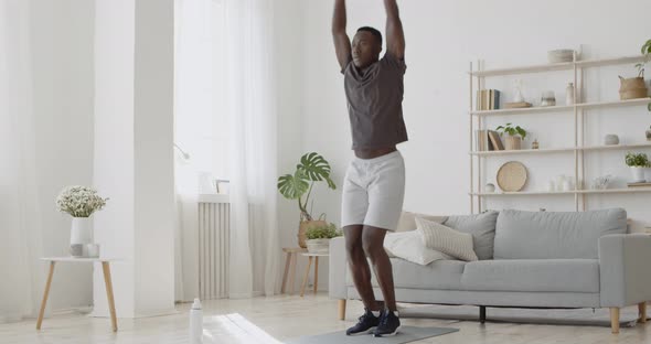 Young Active African American Man Doing Jumping Jack Exercise at Home, Intensive Cardio Workout