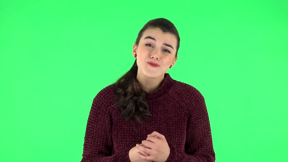 Girl Looks with Tenderness with Folded Arms in Front of Her. Green Screen