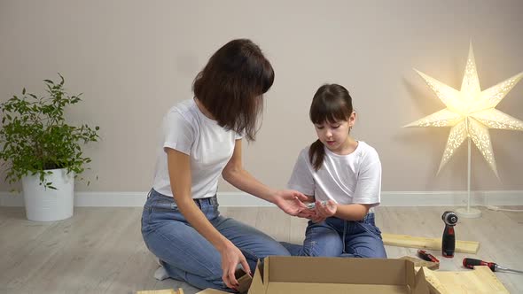 Happy Family Mother and Daughter Unpack New Wooden Furniture Together