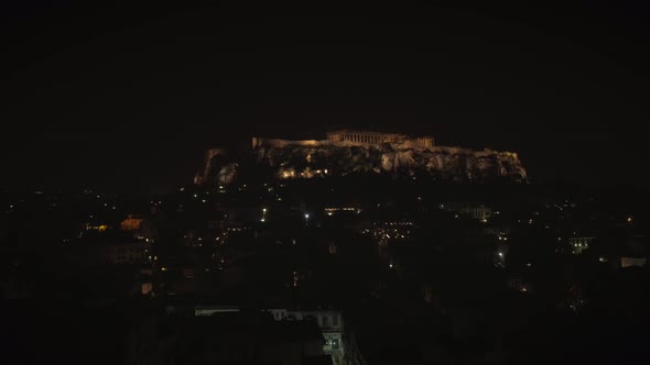 Aerial view of the parthenon temple on acropolis hill at night in Athens.