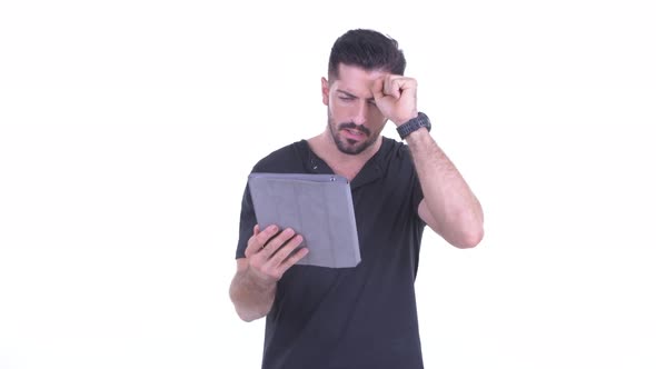 Stressed Young Bearded Man Using Digital Tablet and Getting Bad News