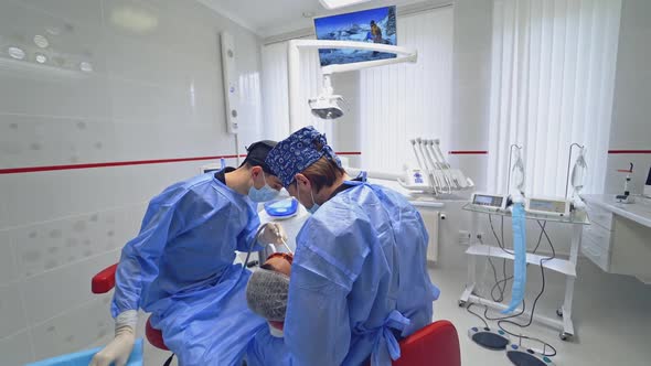 Specialists treating patient's teeth. Dentist with his assistant working in dental office. 