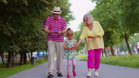 Smiling Senior Grandmother Grandfather with Granddaughter Playing Squeezing Antistress Toy Game