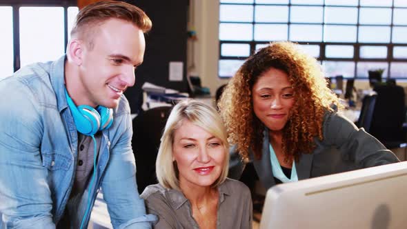 Businesswoman interacting with coworkers while working on computer