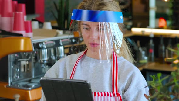 Female Worker of Cafe is Using Tablet Wearing Face Shield From Coronavirus Infection