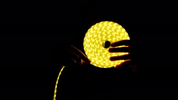 Yellow LED Strip Coil Decorative Lighting in Hand on Dark Background