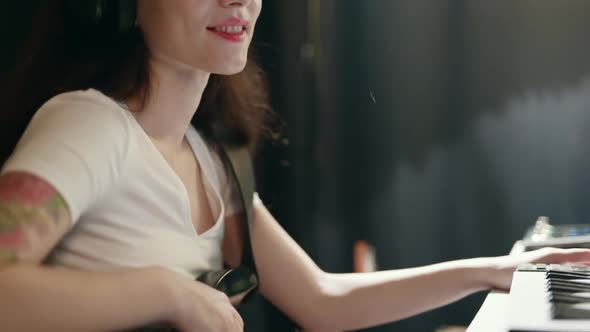 Female Musician Recording Song in Home Record Studio. Young Woman Playing Guitar and Synthesizer