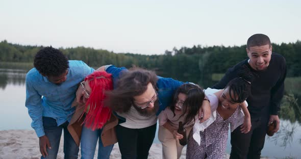 A Group of Best Friends of Different Nationalities Embrace in a Row Holding Bottles in Their Hands