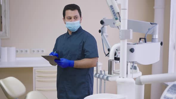 Focused Middle Eastern Man in Face Mask and Gloves Writing in Slow Motion Looking at Dental