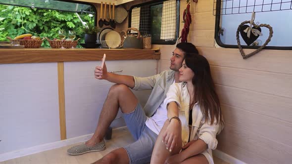 Beautiful Couple Sitting on the Floor in the Stylish Kitchen in Van and Doing Selfie Using