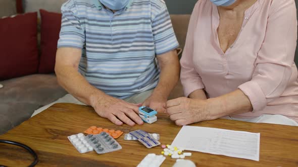 Senior Couple Grandfather and Grandmother Monitoring Oxygen Saturation with Digital Pulse Oximeter