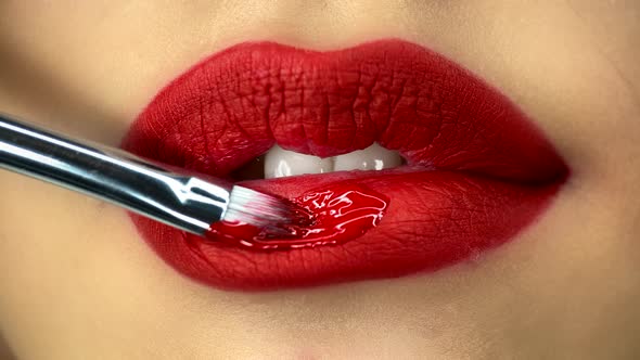 Creative Makeup Artist Puts on a Lipgloss on a Model's Lips