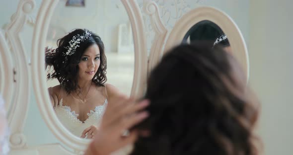 Bride Sits in Front of the Mirror  Looks at the Reflection