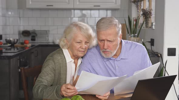 Married Couple of Retirement Age Keeps Accounts Makes an Online Payment Using a Laptop Sitting at
