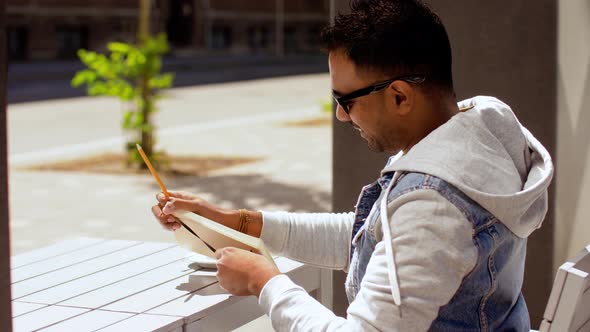 Man with Notebook and Coffee at Street Cafe