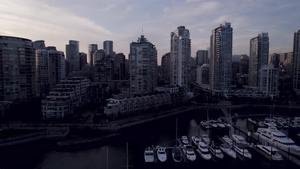 Touristic port and skyscrapers at sunset, Vancouver city in Canada. Aerial sideways