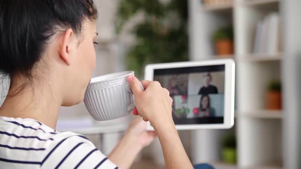 Tilt up video of woman drinking coffee during video conference