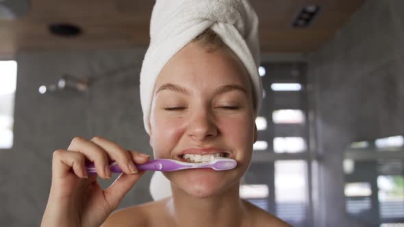 Front view of caucasian woman brushing teeth in hotel