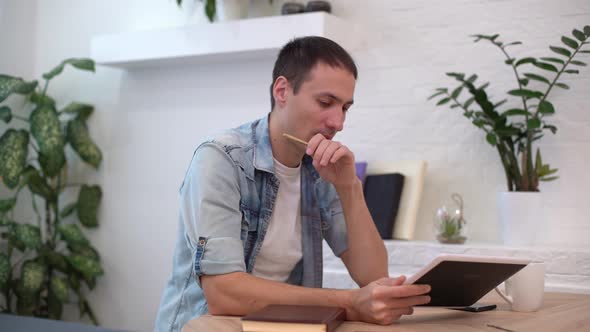 Man Working with Tablet at the Table at Home