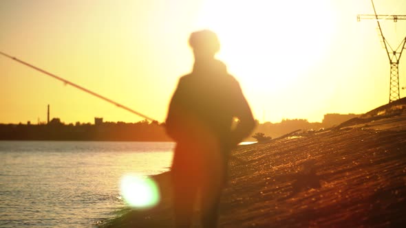 Shifting Focus From Landscape To Silhouette of a Fisherman Standing Against the Sunset