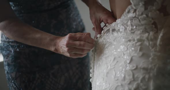 Mother Buttoning Lacy Expensive Wedding Dress of Her Daughter Back Closeup