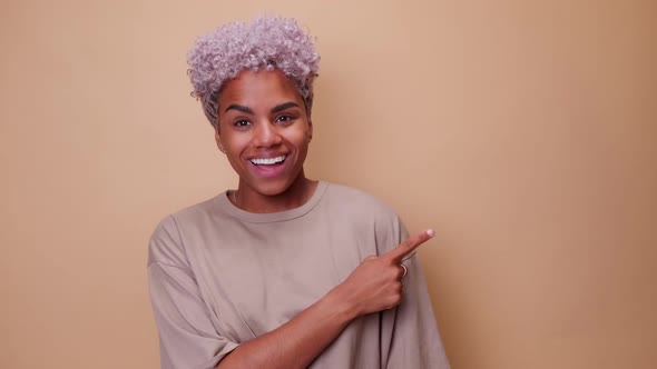 Young Happy African American Woman Smiling and Showing with Hand on Copy Space