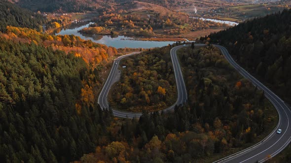 Aerial Drone View of Car and Cargo Bus Moves Along a Serpentine Forest Mountain Road in Western