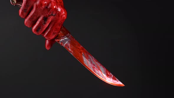 Man Holding Knife with Bloody Hand on Black Background