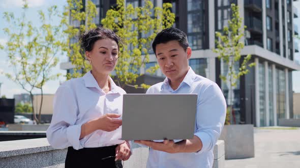 Multicultural Company Leaders Discussing Project Result Use Laptop App Outside