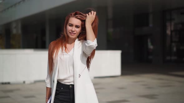 Beautiful confident business woman with red hair in fashion clothes smiles
