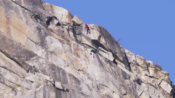 Young Fit Man in Bright Red Jacket Lead Rock Climbing on Sport Route RED Camera