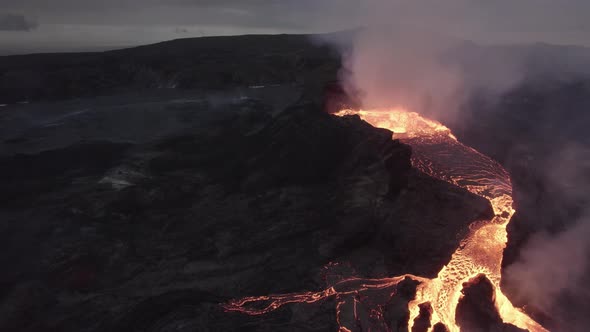 Aerial drone view towards a splattering magma crater, active Volcano surface