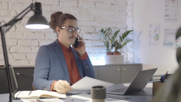 Quirky Businessman Talking on Mobile Phone and Looking at Document