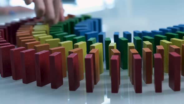 Line up of Dominoes in Rainbow Falling Colors with LGBT Colors of a Hand