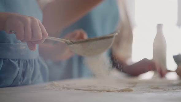 Little Girl is Helping Mother During Cooking Pie or Bun Daughter is Kneading Dough and Pouring Flour