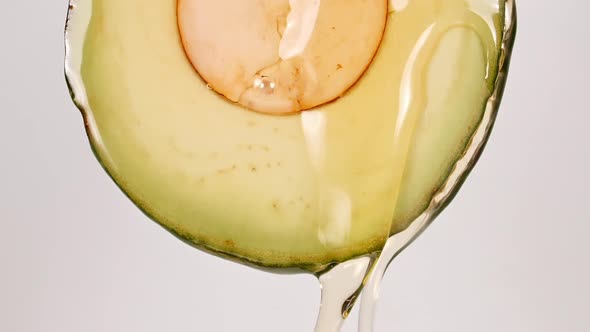 Slow Motion of Flowing the Juice and Oil Stream From Avocado Slice on White Background