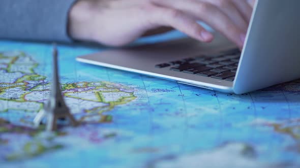 Tourism Blogger Posting Travel Tips, Typing on Laptop, Toy Eiffel Tower on Map