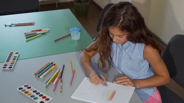 Young Schoolgirl Smiling To the Camera While Drawing