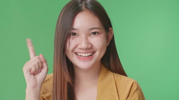 Young Asian Woman Thinking About Something Then Raising Her Index Finger In Green Screen Studio